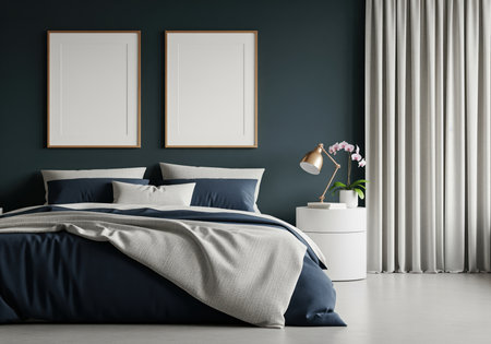 A cozy modern bedroom interior features a large bed with navy blue and gray bedding set against a dark teal wall, flanked by a white nightstand, gold lamp, and two blank vertical mockup frames.の素材