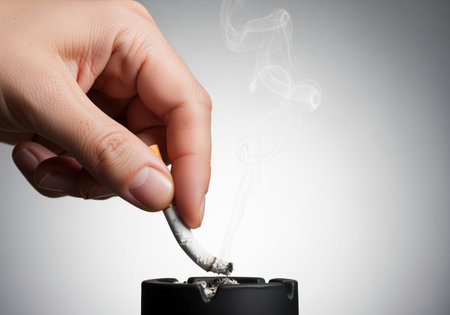 A close up studio shot of a hand extinguishing a burning cigarette butt in a black ceramic ashtray, symbolizing the decision to quit smoking and embrace a healthier lifestyle.の素材