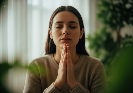 A peaceful portrait of a young woman with her eyes closed and hands clasped in a prayer position, symbolizing faith, meditation, and spiritual well being. this image conveys tranquility and deep introspection.の素材
