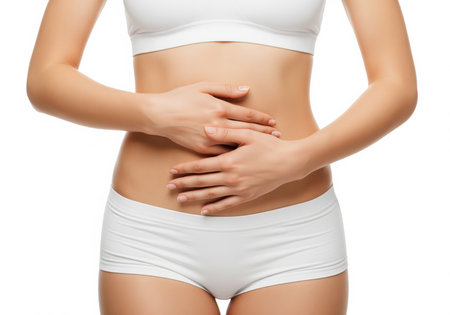 Close up of a fit woman midsection wearing white underwear, holding her hands over her abdomen. this image is ideal for concepts related to fitness, digestion, weight loss, and feminine health.の素材