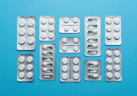 Various pharmaceutical blister packs containing white tablets and capsules are neatly arranged, representing modern medicine, prescription drugs, and healthcare supplies.の素材