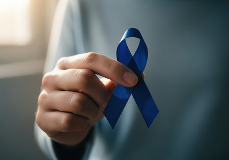 A close up shot of a hand gently holding a deep blue awareness ribbon, symbolizing solidarity, support, and hope for various health conditions like prostate or colon cancer. this image conveys compassion and advocacy.の素材