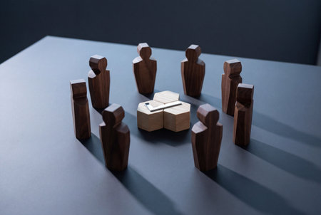 Dark wooden figurines stand in a circle facing a central silver check mark on hexagonal blocks to symbolize collective agreement and successful task completion.の素材