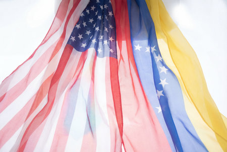 The national flag of the united states of america hanging next to the flag of venezuela representing diplomatic relations and political cooperation between the two countries.の素材