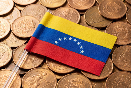 A small textured national flag of venezuela lies on a large pile of scattered vintage copper coins representing financial concepts and national economy or inflation issues.の素材