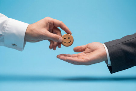 A hand in a white shirt passes a wooden smiley face token to an open hand against a blue background to symbolize positive customer feedback and excellent service satisfaction.の素材