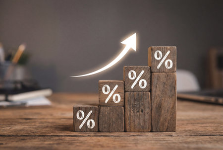 Wooden blocks of increasing height featuring white percentage symbols sit on a desk beneath a glowing white arrow pointing upward to symbolize financial growth and rising rates.の素材