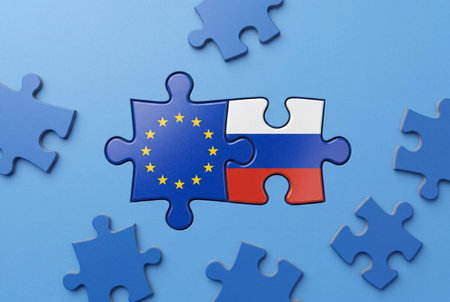 Jigsaw puzzle pieces interlocking with European Union and Russian flags on blue surface representing international relations and cooperation conceptsの素材