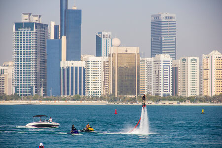 ABU DHABI - MARCH 31, 2013  Group of men doing water sports in front of skyline taken on March 31, 2013 in Abu Dhabi, United Arab Emirates のeditorial素材