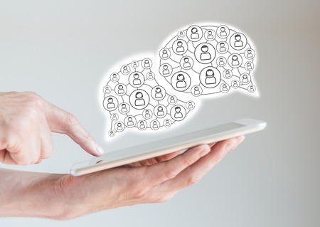 Mobile digital tablet computer in male hands with fingers pointing while browsing a social network Visualized by speech bubbles and Network of People via icons. Mobile computing concept.の写真素材