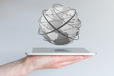 Male hands holding tablet or large smart phone in order to connect to the World Wide Web. Concept of mobile computing and the Internet. Visualization with world and connecting lines.の写真素材