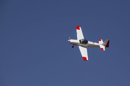 Top view of Small white airplane flying on clear blue sky