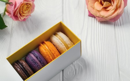 Macarons box with pink roses on white wooden tableの写真素材