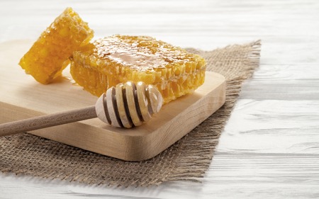 Honeycomb and honey dipper on wooden table