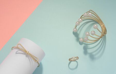 Golden pearl bracelet and golden ring on pastel color background with pink copy space