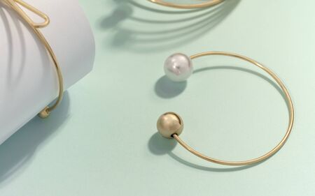 Modern Golden and pearl bracelet with sharp shadow on green background
