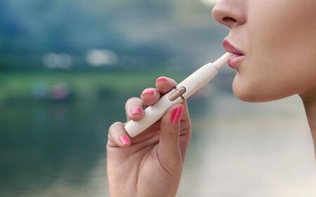 Adult female face profile view smoking electronic cigarette outdoor