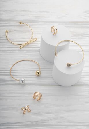 Top view of golden bracelets and rings collection on white wooden surface with copy spaceの写真素材