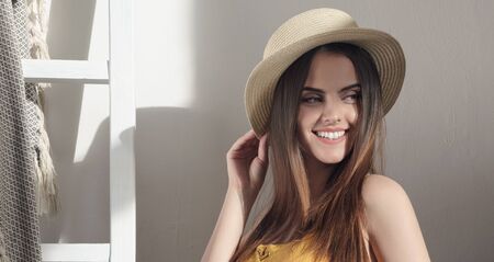 Panoramic shot of pretty girl holding her straw hat and smiling in sun light