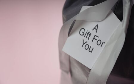 Card on gift box with text : A Gift For You on pink background with copy space