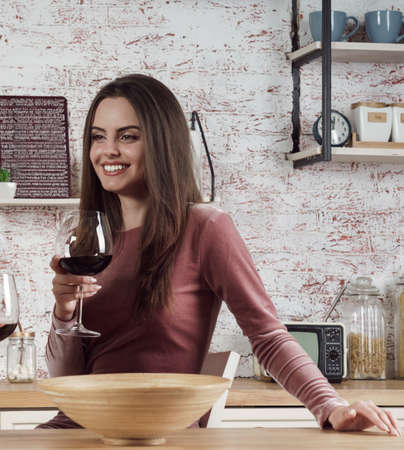 Cheerful brunette woman holding a glass of red wineの写真素材