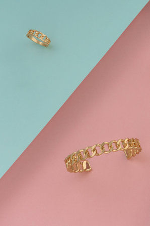 Chain shape golden bracelet and ring on slanted paper background