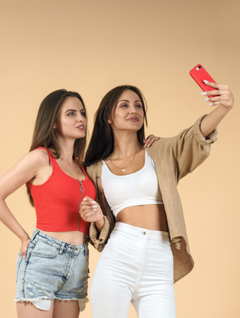 Two women taking selfie on beige backgroundの写真素材