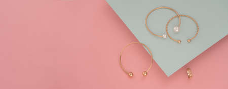 Panoramic shot of golden bracelets on pastel colors backgroundの写真素材