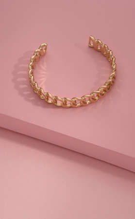Top view of chain shape golden bracelet on pink backgroundの写真素材