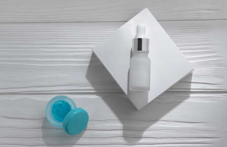 Pipette bottle on white box and open blue gel on white wooden table