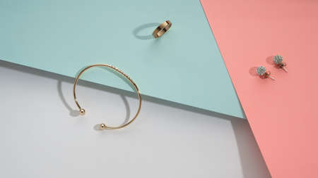 Flat lay of Golden accessories on geometric pastel colors background