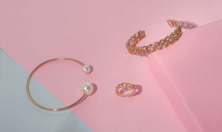 Golden jewelries bracelets and ring on pastel colors paper background