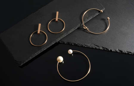 Gold bracelets with pearls and earrings pair on black stone plates with copy spaceの写真素材