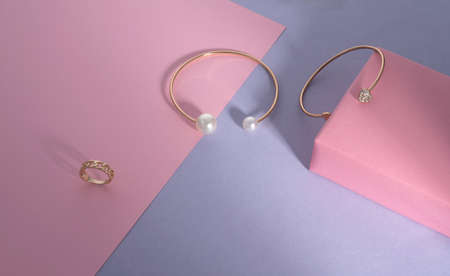 Modern golden accessories on pink and purple paper backgroundの写真素材