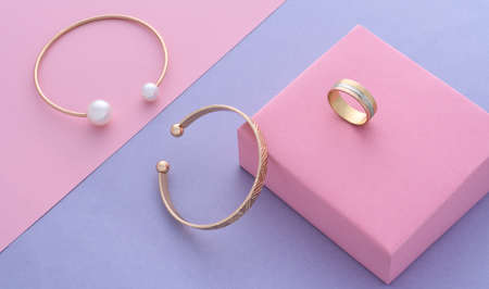 Top view of modern gold bracelets and ring on pastel colors paper backgroundの写真素材