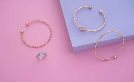 Top view of modern golden jewelries on pink and purple background with copy space
