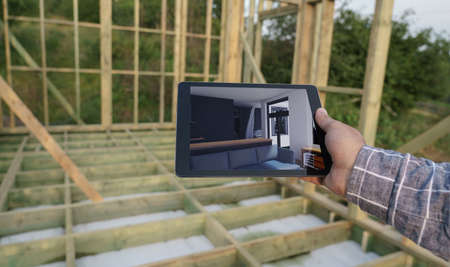 Man holding digital tablet with interior design images in construction site with copy spaceの写真素材