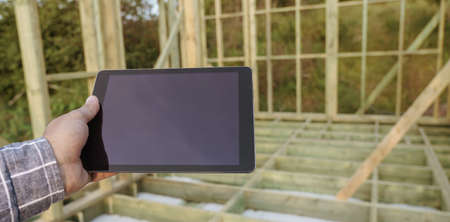 Male hand holding digital tablet in construction site with empty screenの写真素材