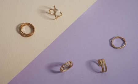 Top view of golden rings collection on purple and beige backgroundの写真素材