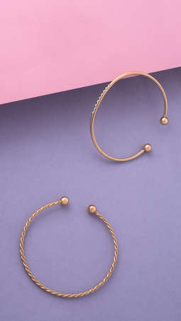 Vertical shot of two modern bracelets on pink and purple background with copy spaceの写真素材
