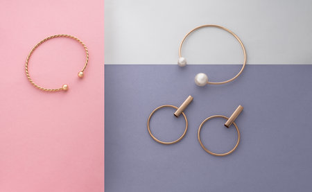 Flat lay of golden jewelries collection on pastel colors background