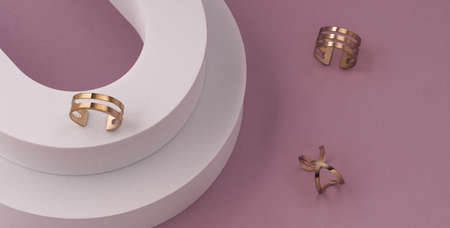 Modern golden rings collection on white platform on pink background