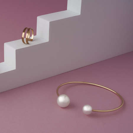 Golden with pearls bracelet and golden ring on white podium on pink background with copy spaceの写真素材