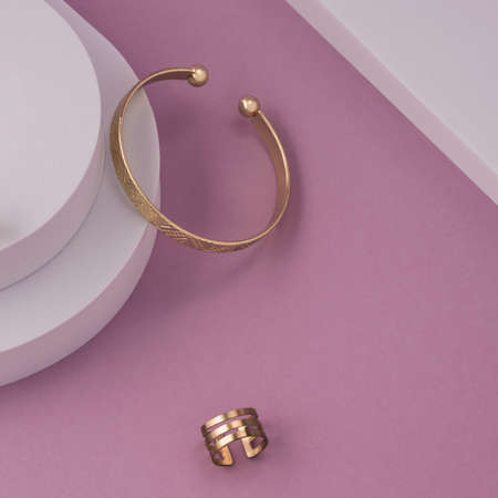 Geometric pattern bracelet and ring on white and pink background with copy spaceの写真素材