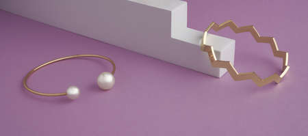 Zigzag shape and modern golden with pearls bracelets on white and purple background with copy spaceの写真素材