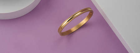 Panorama of modern golden bracelet on pink and white backgroundの写真素材