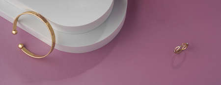 Panoramic shot of geometric pattern bracelet and ring on white and pink background with copy spaceの写真素材