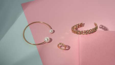 Golden with pearl and chain shape bracelets and ring on pastel colors backgroundの写真素材