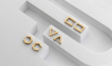 Top view of modern geometric golden earrings on geometric white background with copy spaceの写真素材
