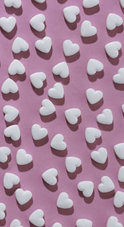 Vertical seamless pattern of white hearts on pink backgroundの写真素材